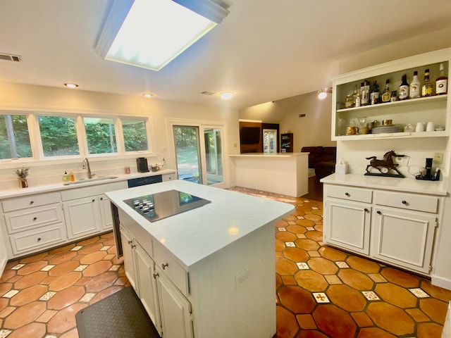 kitchen with a skylight, white cabinetry, sink, black appliances, and a kitchen island