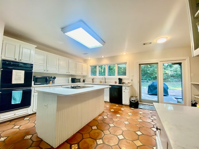 kitchen featuring black appliances, white cabinetry, a kitchen island, and sink