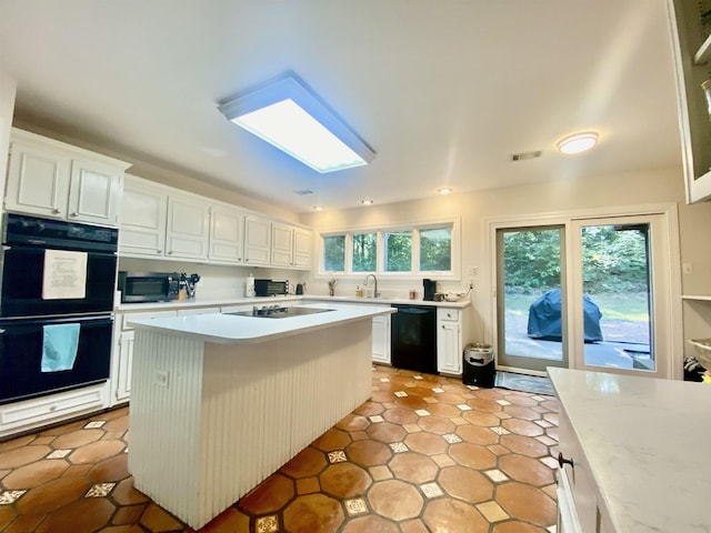 kitchen with white cabinets, light countertops, a sink, and black appliances