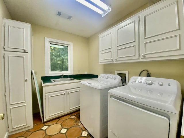 laundry room with visible vents, washing machine and clothes dryer, a sink, tile patterned floors, and cabinet space