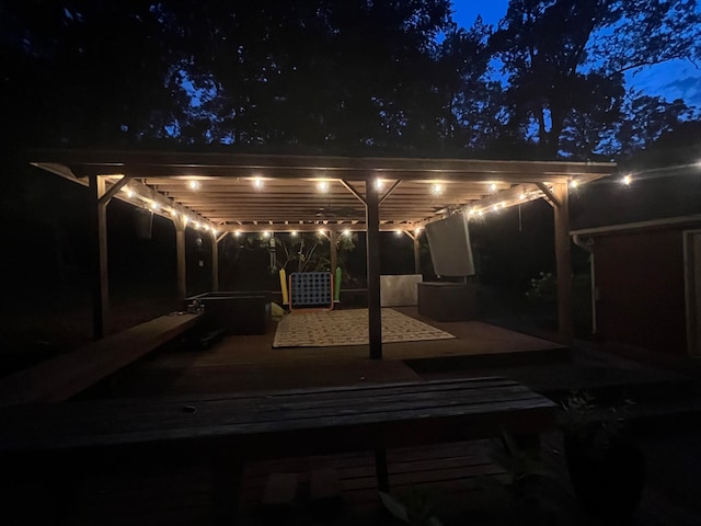 patio at night featuring a pergola and a deck