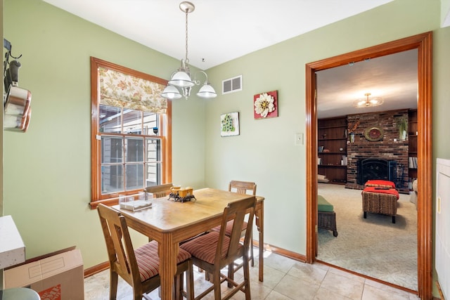 tiled dining area with a fireplace and a notable chandelier