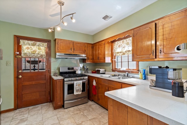 kitchen featuring stainless steel gas range, sink, and light tile patterned flooring