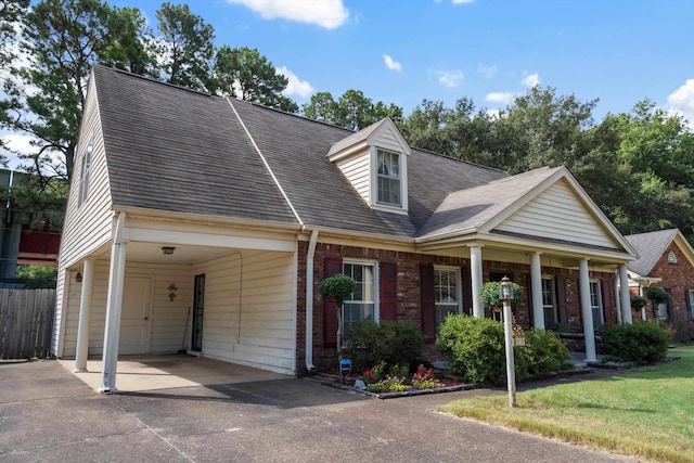 cape cod home featuring a carport, covered porch, and a front yard