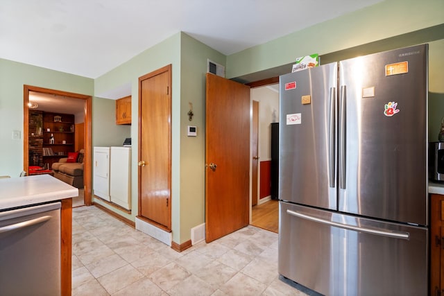 kitchen with washer and dryer, stainless steel appliances, and light tile patterned flooring