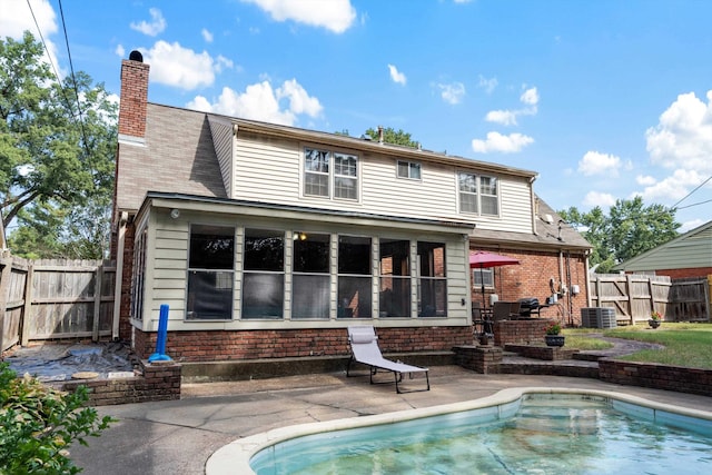 rear view of property featuring cooling unit, a fenced in pool, and a patio