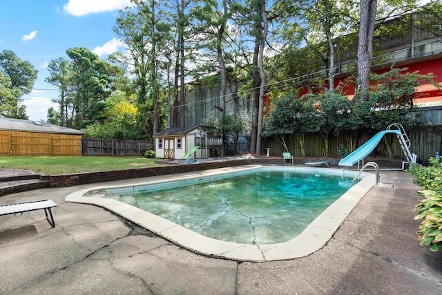 view of swimming pool featuring a water slide, a patio, and a shed