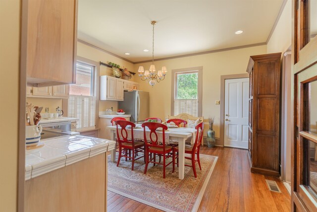 dining space featuring crown molding, light hardwood / wood-style flooring, and a notable chandelier