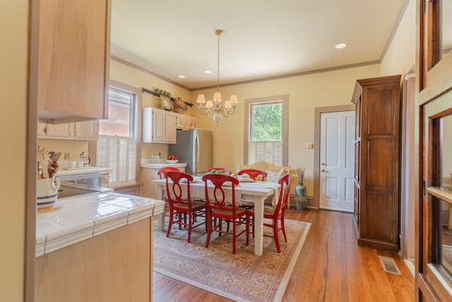 dining space featuring light wood-type flooring, visible vents, recessed lighting, crown molding, and a chandelier