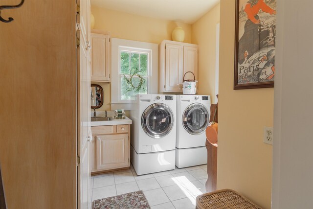 laundry area with light tile patterned floors, cabinets, washing machine and clothes dryer, and sink