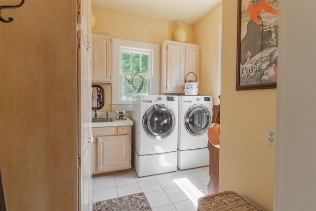 laundry area featuring washing machine and dryer, light tile patterned flooring, cabinet space, and a sink