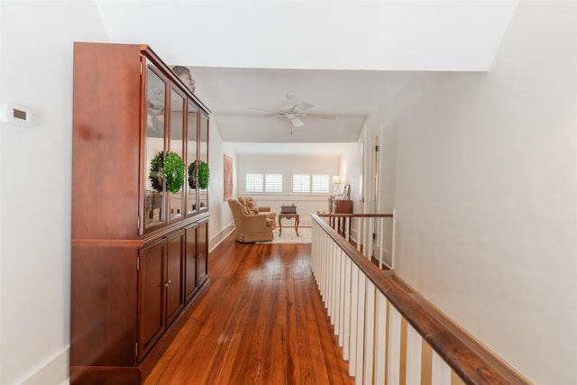 hallway with dark wood finished floors and an upstairs landing