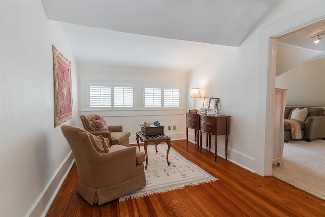 living area with baseboards, lofted ceiling, and wood finished floors