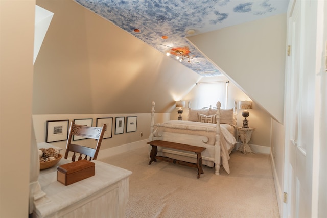 bedroom with baseboards, vaulted ceiling with skylight, and light colored carpet