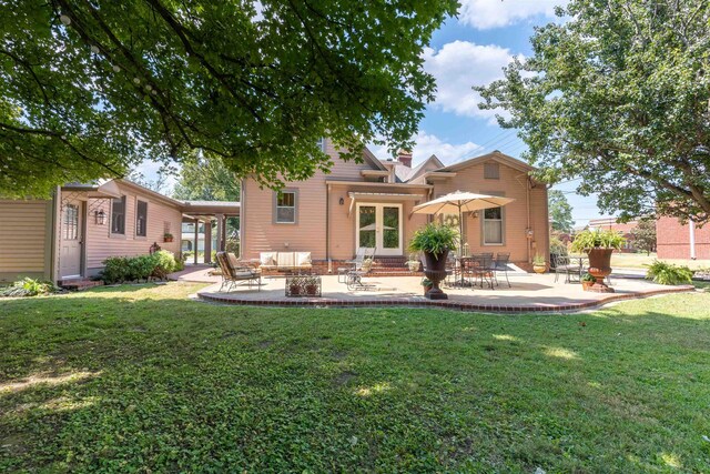 rear view of house featuring a lawn and a patio