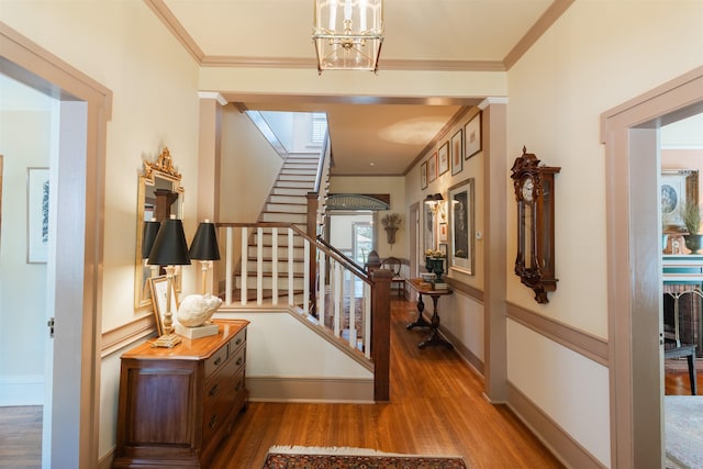 foyer featuring baseboards, wood finished floors, ornamental molding, and stairs