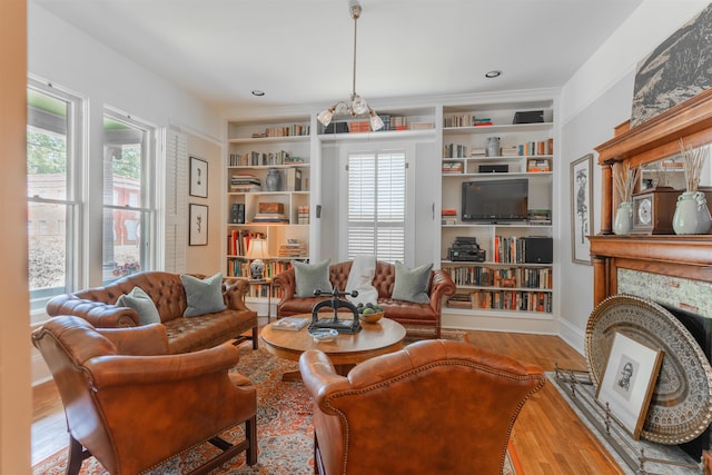 living room with built in shelves, wood finished floors, and a large fireplace