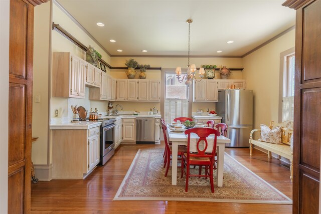 kitchen with crown molding, hardwood / wood-style floors, stainless steel appliances, and a notable chandelier