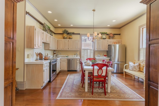 kitchen featuring crown molding, tile counters, wood finished floors, a notable chandelier, and stainless steel appliances