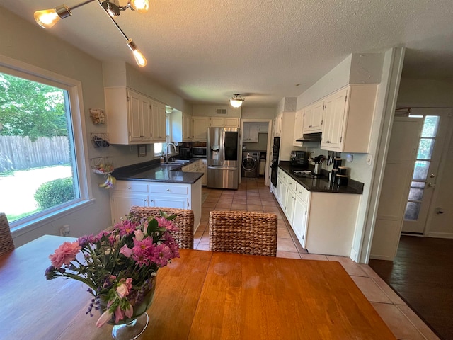 kitchen with white cabinets, appliances with stainless steel finishes, washer / dryer, and sink