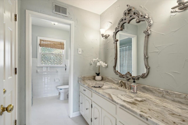 bathroom featuring vanity, toilet, tile walls, and walk in shower