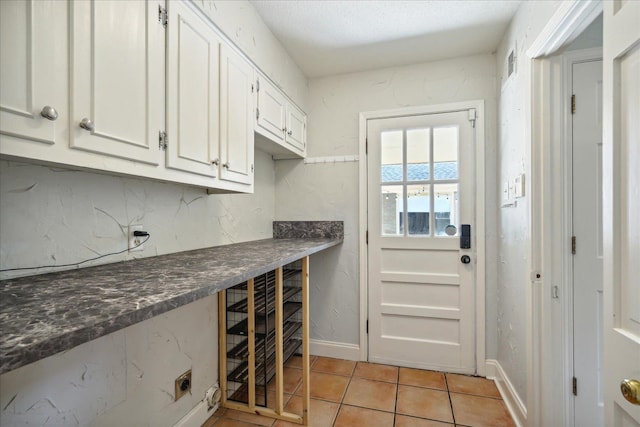 interior space with a textured ceiling, white cabinets, and light tile patterned flooring