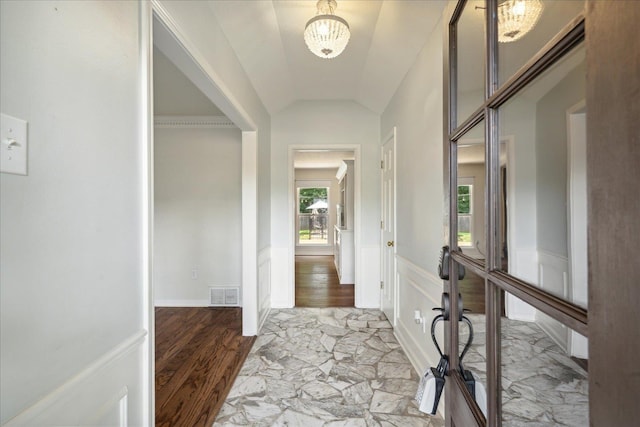 entrance foyer featuring light wood-type flooring, lofted ceiling, and a chandelier