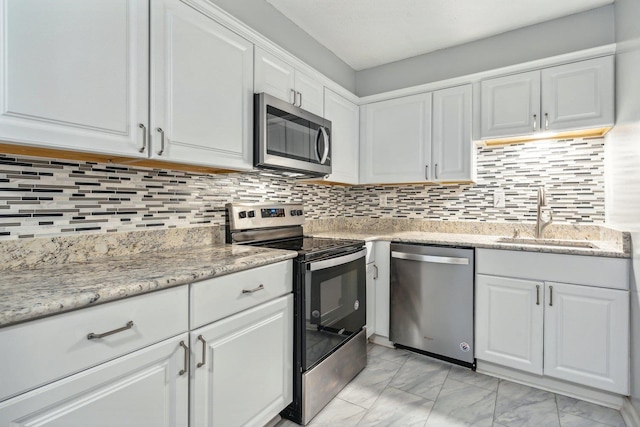 kitchen with decorative backsplash, appliances with stainless steel finishes, marble finish floor, white cabinetry, and a sink