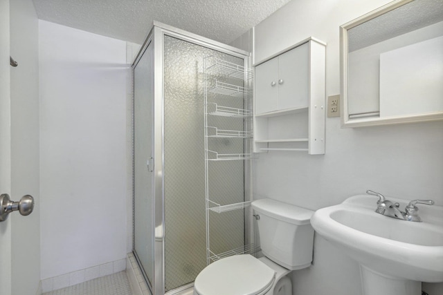 bathroom with tile patterned flooring, walk in shower, toilet, sink, and a textured ceiling