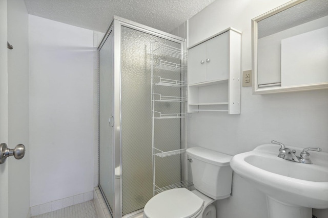 bathroom with a textured ceiling, a stall shower, and toilet