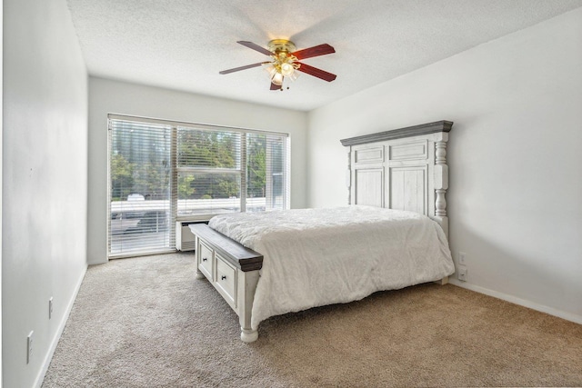 bedroom with a ceiling fan, light colored carpet, baseboards, and a textured ceiling