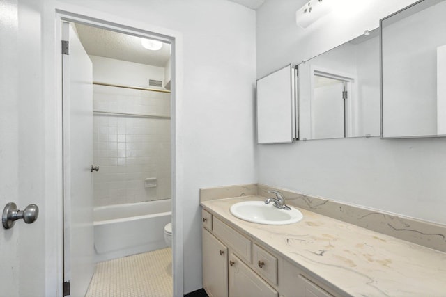 full bathroom featuring toilet, tile patterned flooring, tiled shower / bath, vanity, and a textured ceiling