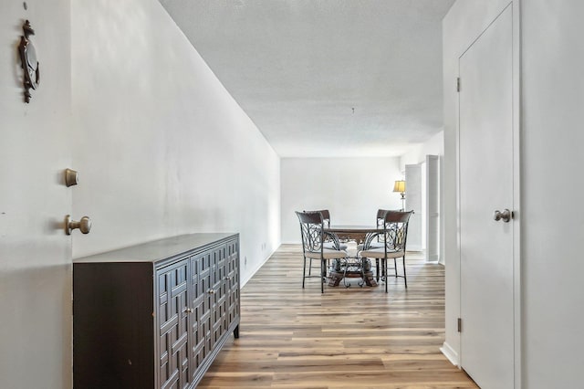 corridor with a textured ceiling and wood-type flooring