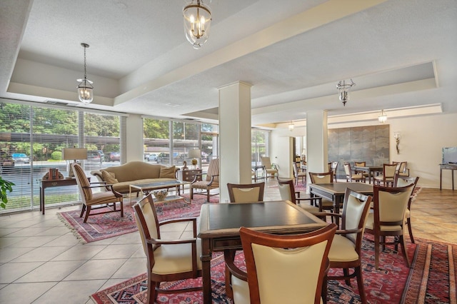 tiled dining space featuring a tray ceiling, a chandelier, and a textured ceiling