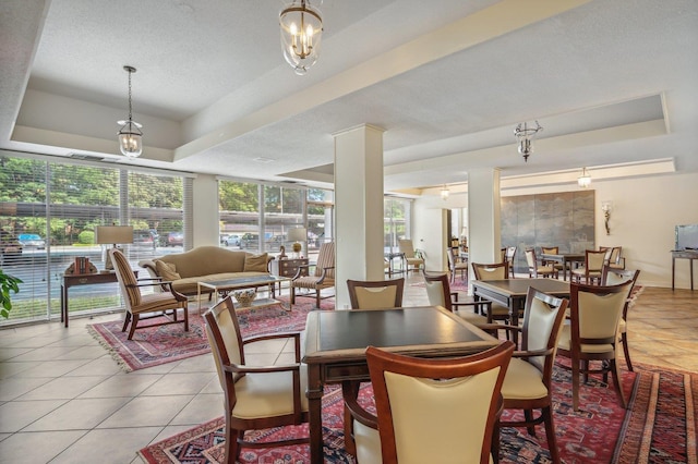 dining room with a raised ceiling, light tile patterned floors, and a textured ceiling