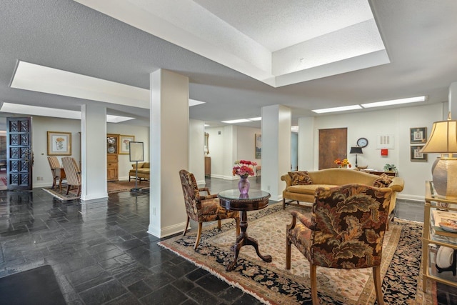 living area featuring stone finish flooring, baseboards, and a textured ceiling