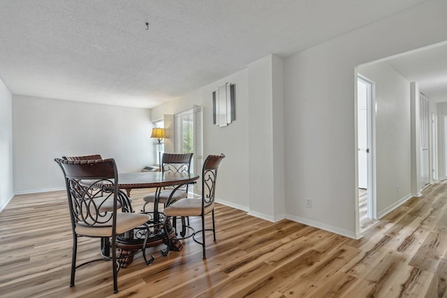 dining room featuring a textured ceiling and light wood-type flooring