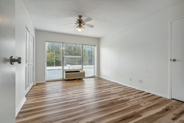 unfurnished room featuring a textured ceiling, ceiling fan, hardwood / wood-style floors, and an AC wall unit