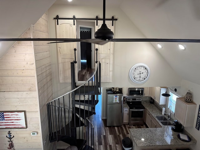 interior space featuring hardwood / wood-style flooring, wooden walls, a barn door, sink, and high vaulted ceiling