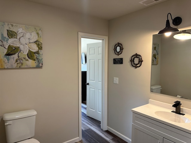 bathroom with vanity, toilet, and hardwood / wood-style flooring