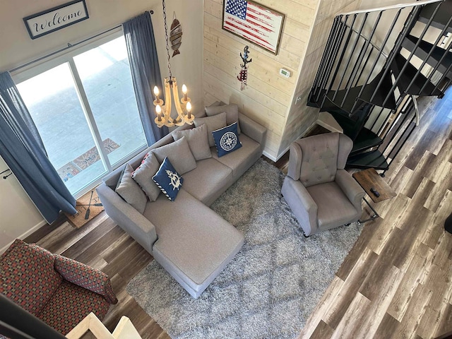 living room with wood-type flooring, a notable chandelier, and wooden walls