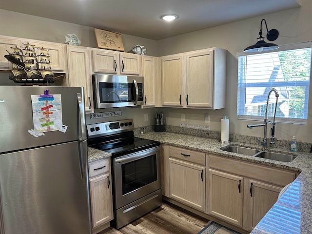 kitchen with hardwood / wood-style floors, stainless steel appliances, sink, light stone countertops, and light brown cabinets