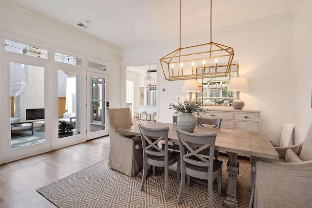 dining area featuring visible vents, crown molding, an inviting chandelier, and wood finished floors