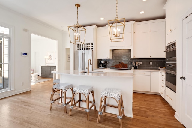 kitchen featuring tasteful backsplash, light wood-style flooring, high quality fridge, a breakfast bar, and a sink