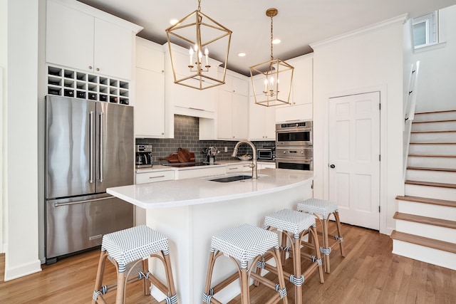 kitchen featuring a sink, white cabinets, light countertops, appliances with stainless steel finishes, and decorative backsplash