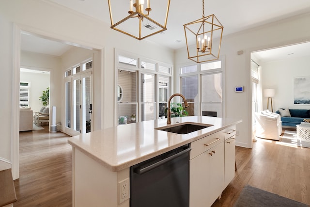 kitchen featuring a notable chandelier, a center island with sink, a sink, light wood-type flooring, and dishwashing machine