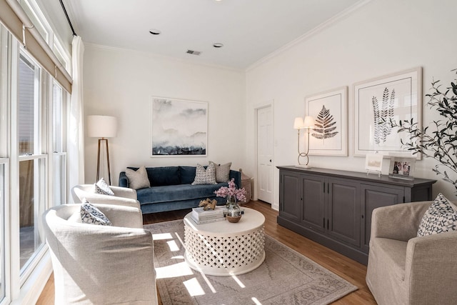 living area with light wood-type flooring, visible vents, and crown molding