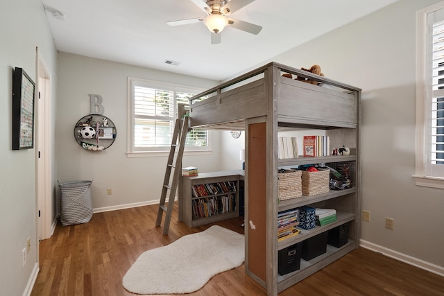 bedroom featuring visible vents, baseboards, ceiling fan, and wood finished floors