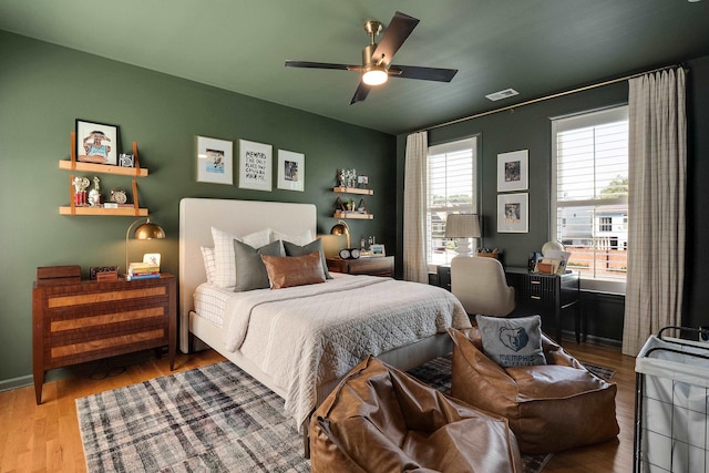 bedroom featuring visible vents, ceiling fan, baseboards, and wood finished floors