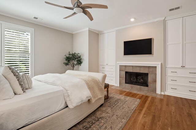 bedroom with light wood finished floors, ornamental molding, a fireplace, and visible vents